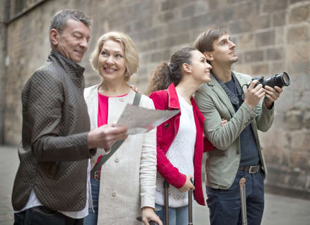 group of tourists with suitcases and camera walk along the historic streets of European cityの写真素材
