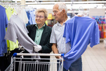 older european couple chooses tee shirt in clothing department of supermarket