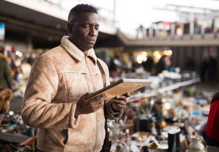 AfricaAmerican man chooses antiques on the flea market