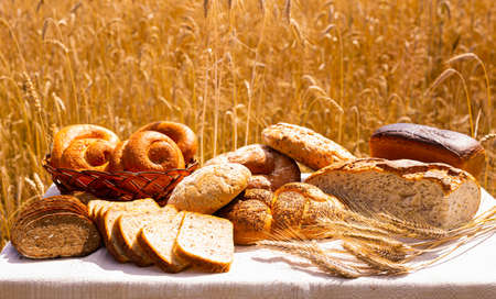 loaves of various types of bread and sliced bread on a table in wheat field