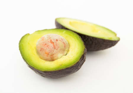 ripe halved avocado with bone on white background