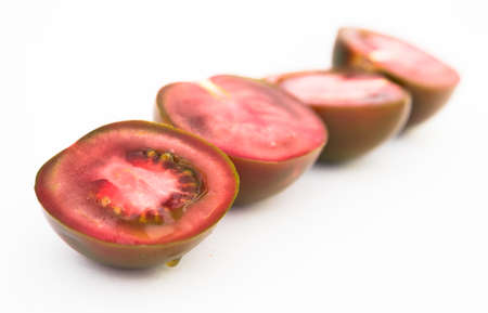 ripe black halves of tomatoes on white backgroundの写真素材
