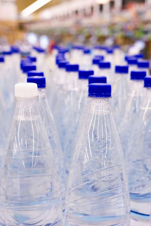 plastic water bottles with blue caps in supermarketの写真素材