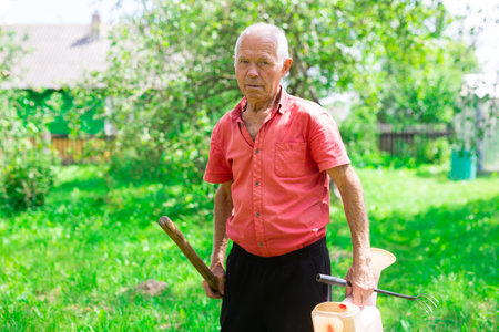 elderly man farmer leaves the vegetable garden after a working dayの写真素材