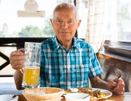 old man posing with a mug of beer at lunch in a restaurantの写真素材