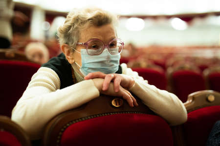 Mature seniorÐ° in protection masks are interested in watching ballet performance in theater hall