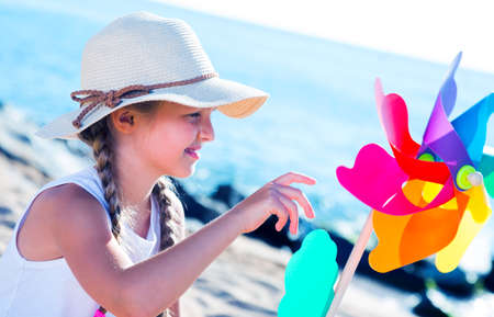 blonde girl with Pinwheel on beachの写真素材