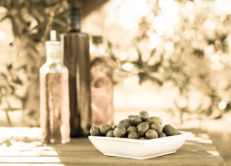 still life with green olives and oil on table in olive groveの写真素材