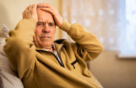old man winces with headache due to noiseの写真素材