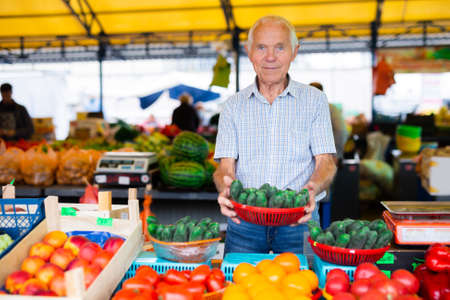 mature european man selling tomatoes in marketの写真素材