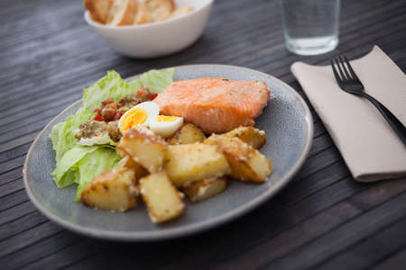 baked salmon fillet with fried potato wedges, homemade guacamole and quail eggs halvesの写真素材