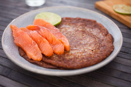 salted salmon fillet with buckwheat pancakes and limeの写真素材