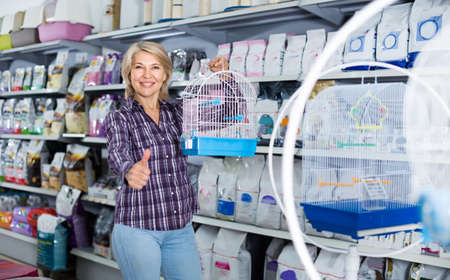mature woman purchasing bird cage in petshopの写真素材