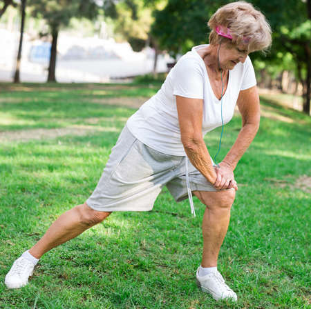 Senior woman stretching outdoors before runningの写真素材
