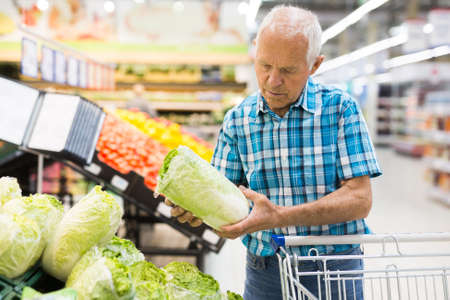 old age man choosing pekinensis cabbage in supermarketの写真素材