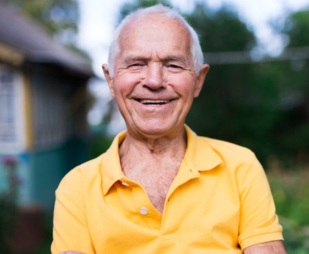 Portrait of an elderly man 70 years old in his garden on a summer sunny day