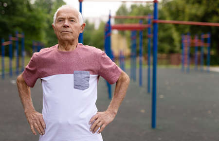European senior man standing in outdoor playground in city park.の写真素材