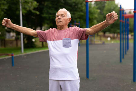 Elderly man doing gymnastic exercises in summer parkの写真素材