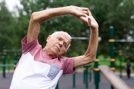 Sportive old man warming up before his outoor training in workout station.の写真素材