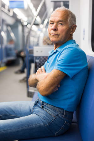Portrait of elderly european man 75 years old sitting in underground carriageの写真素材