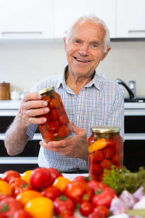 old man holding jars of pickled tomatoes and smilingの写真素材