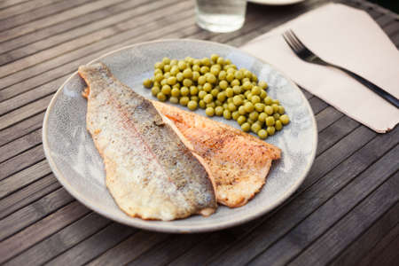 Top view of baked trout fillet served on plate with peas closeupの写真素材