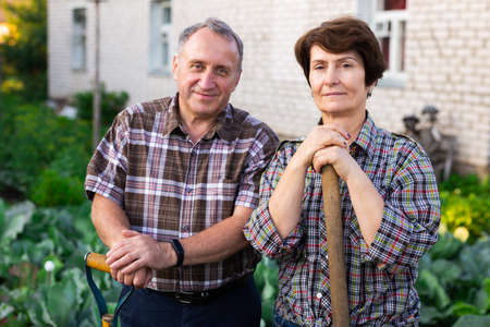 mature farmers posing with a harvest of vegetables in the gardenの写真素材