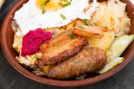 Scrambled eggs with fried bacon and potatoes served on plateの写真素材