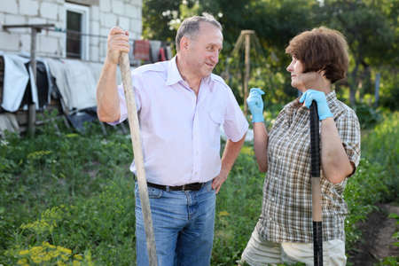 Man and woman gardeners with shovel and bucket while gardening