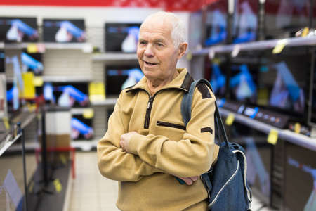 elderly man choosing TV in showroom of electronics storeの写真素材