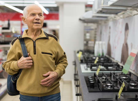elderly man choosing gas stove in showroom of electrical appliance storeの写真素材