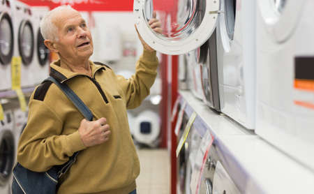 senor man pensioner buying washing machine in showroom of electrical appliance storeの写真素材