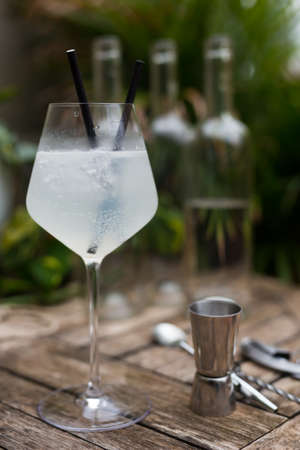 white cocktail with ice in a glass with a stem on a wooden surface