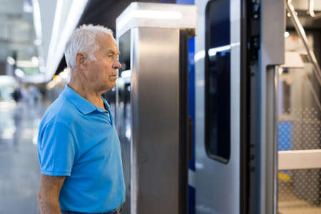 Elderly man getting on modern subway car. Concept of daily city tripsの写真素材
