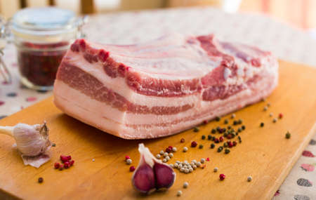fresh piece of pork belly on wooden board with spicesの写真素材