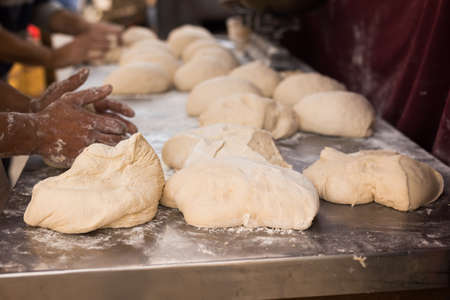 male hands knead yeast dough for baking breadの写真素材