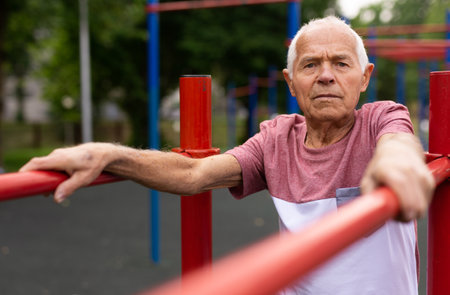 Old man standing between parallel bars outdoorsの写真素材