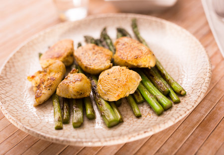 fried chicken breast pieces with asparagus on white plateの写真素材