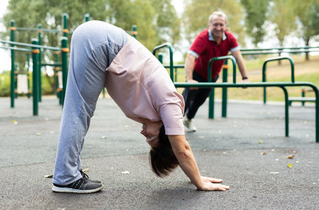 Mature woman doing yoga outdoors in city sports groundの写真素材