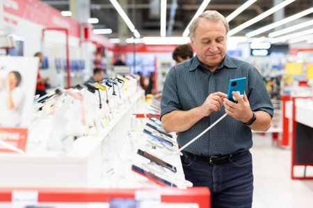 Elderly man chooses mobile phone in store