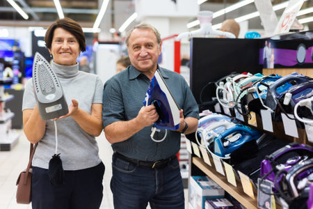 Elderly man and elderly woman choose iron in storeの写真素材