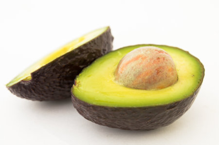 halved avocado with bone on white backgroundの写真素材