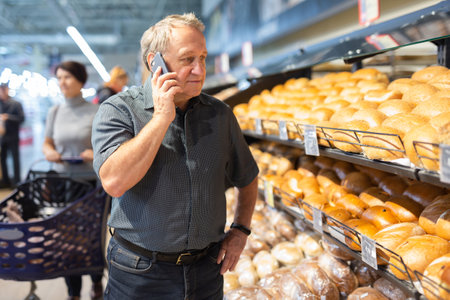 man takes muffins on shelf of bakery sectionの写真素材