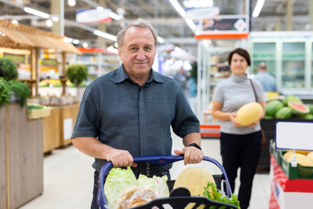 Elderly man with shopping cart shopping in supermarketの写真素材