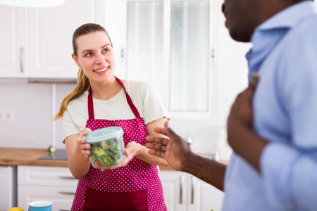 Woman giving container with food to her husband before workの写真素材