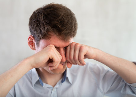 Portrait of young guy with itchy eyes in studioの写真素材