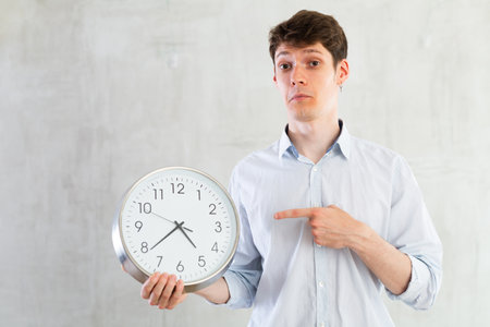 Man with a round big clock in his hands expresses various emotions