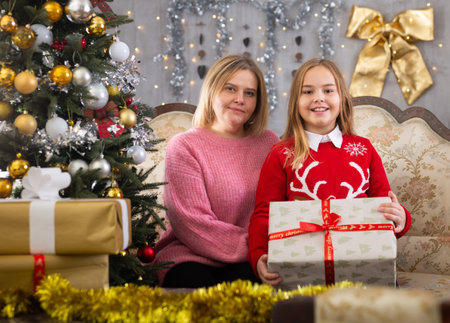 Family is what makes Christmas so special. Mom and daughter together next to the Christmas treeの写真素材