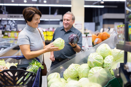 Husband and wife choose and buy fresh cabbage in grocery storeの写真素材
