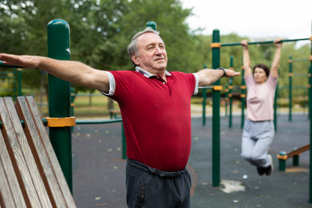 Aged man practicing gymnastics in open-air sports area